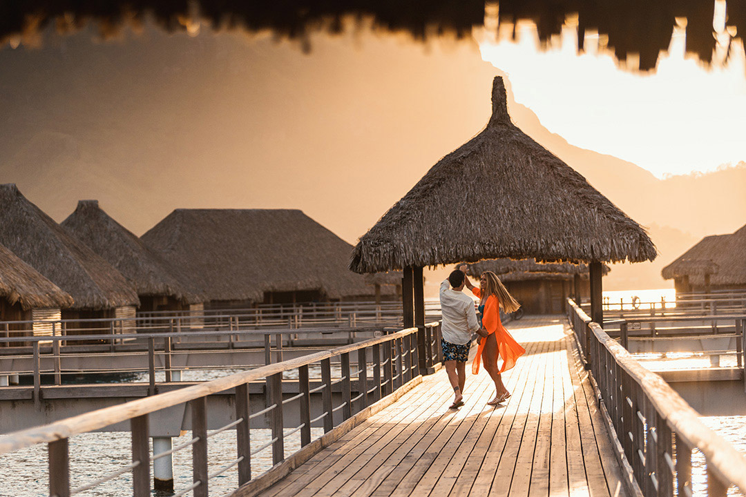 Photo de couple dansant sur le ponton du St Regis Bora Bora pendant le coucher de soleil