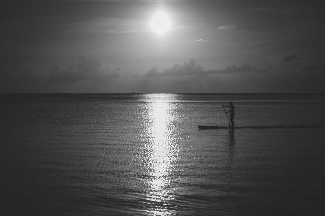 Stand up paddle passant devant le coucher de soleil à Matira