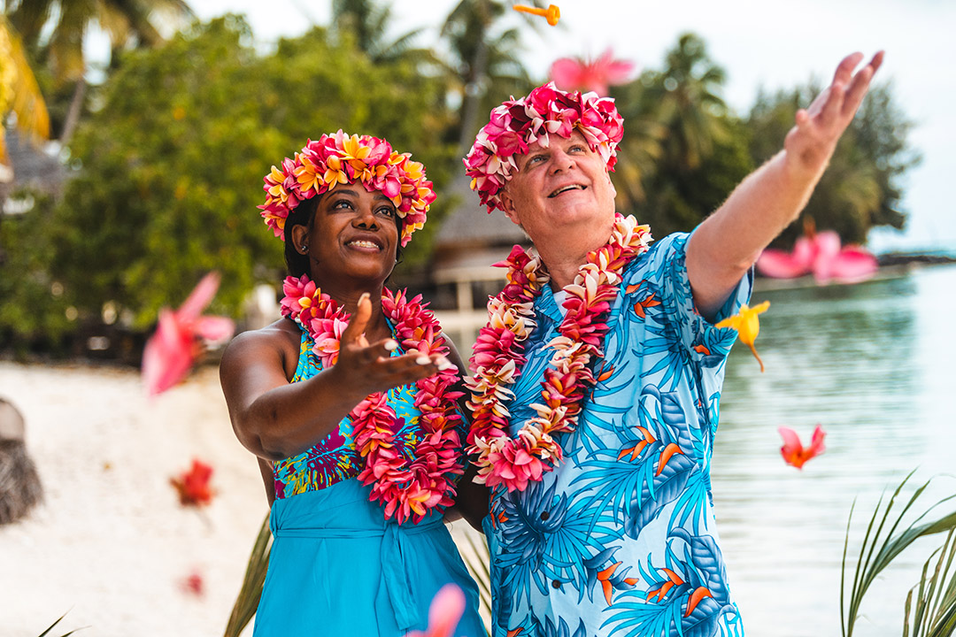 Photographe de mariage tahitien à Bora Bora - Les jeunes mariés reçoivent des fleurs colorées roses et jaunes.