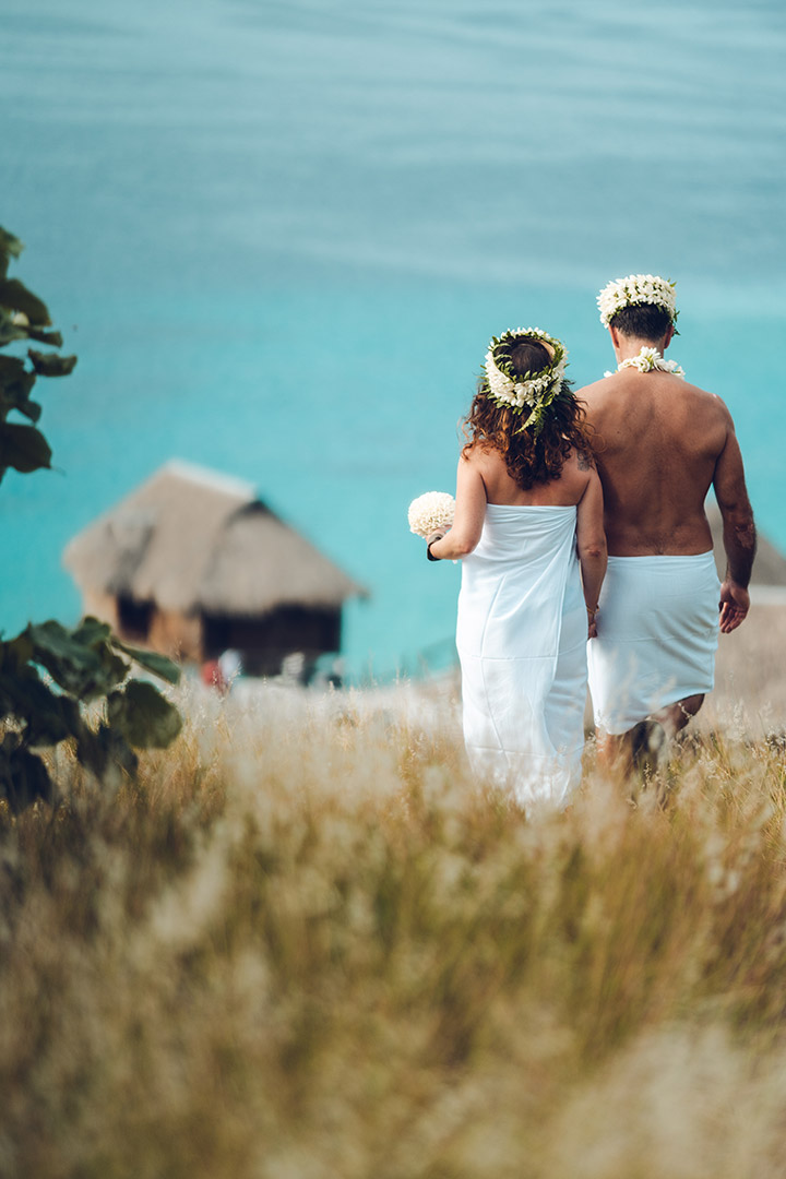 Photo de mariage Polynésien au Sofitel Private Island Bora Bora - le couple marche dans les herbes hautes